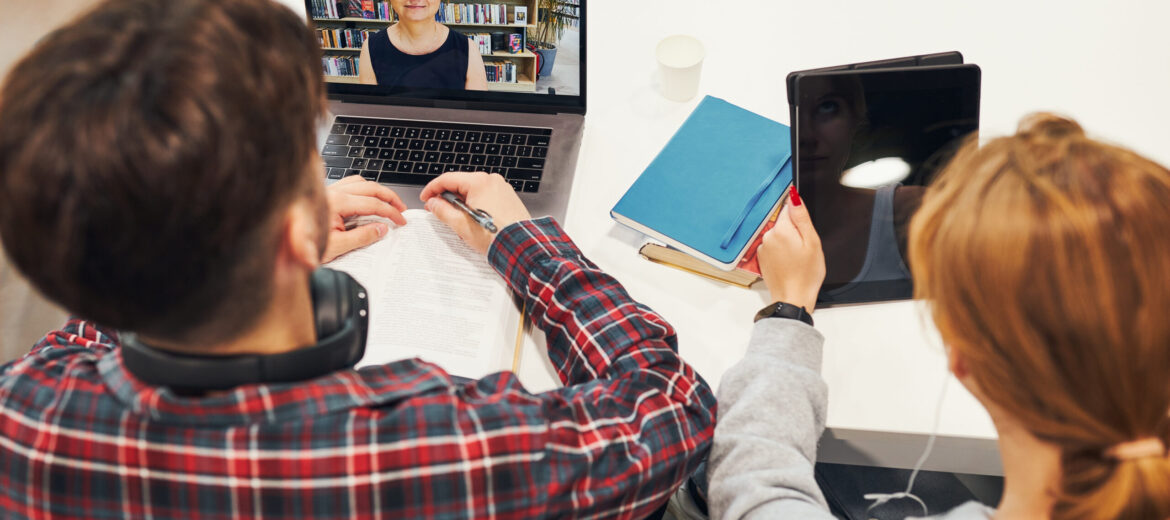 Students learning in university library. Young man having video class on laptop. Girl writing essay and making notes using computer. Focused students studying for college exams. Back to school