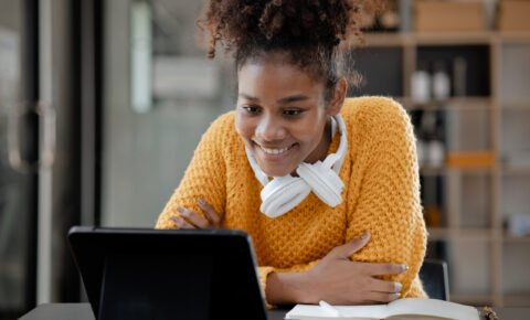 American teenage woman sitting in office with laptop, she is a s