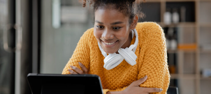 American teenage woman sitting in office with laptop, she is a s