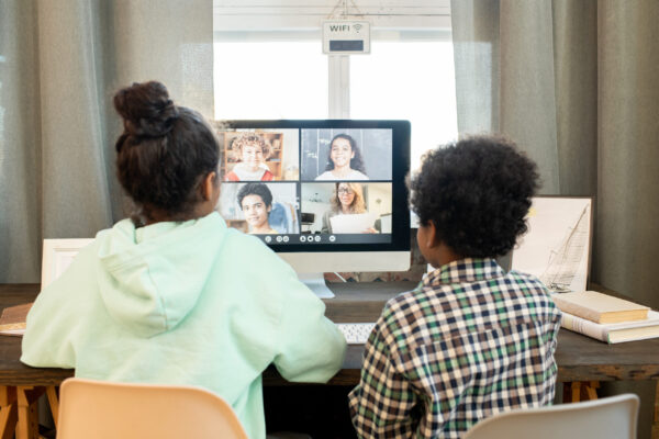 Rear view of diligent schoolchildren in casualwear sitting in front of computer